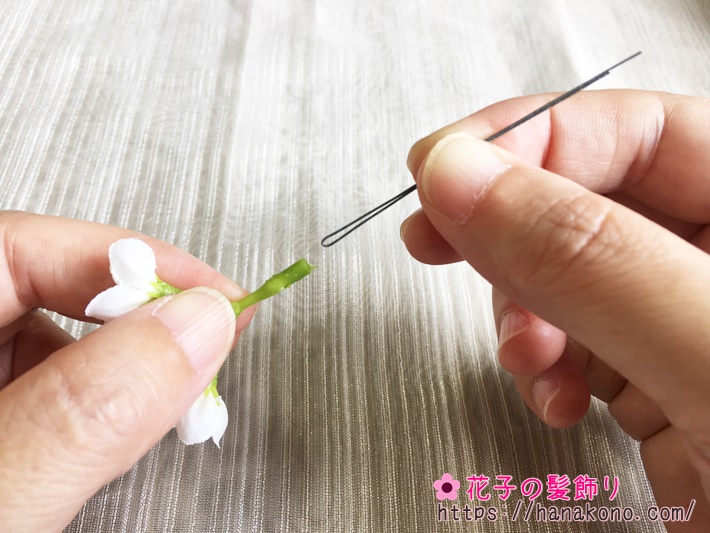 ライラックの花の根元の茎に穴が開いています。そこに13センチ程度に切ったワイヤーを半分に折り、差し込みます。抜けないよう、ワイヤーの折り曲げ部の幅を調節してください